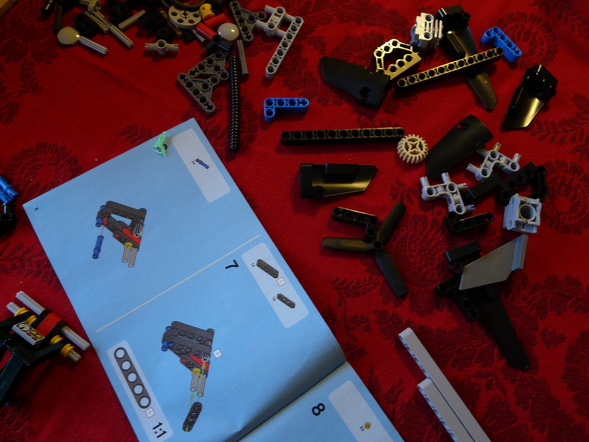 Printed LEGO Technic instructions beside loose pieces