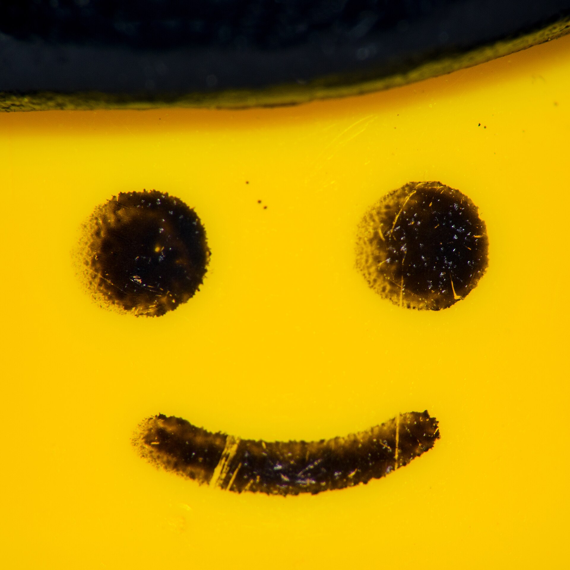 Close-up of a smiling yellow LEGO minifigure head wearing a black hat