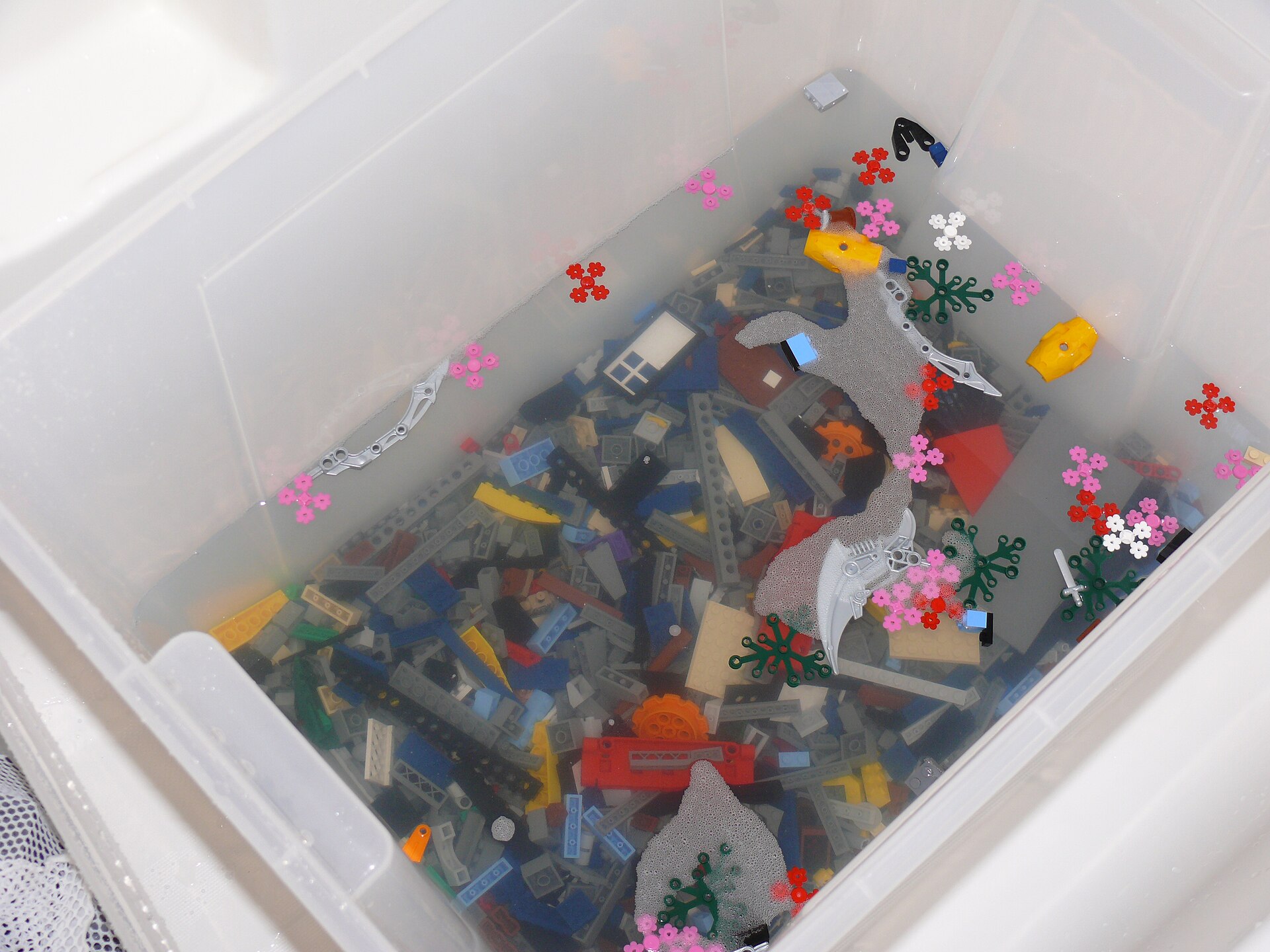 Loose LEGO bricks being washed in a tub of soapy water
