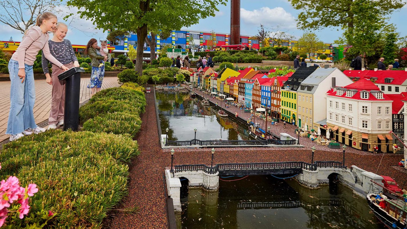 Visitors beside miniature buildings and waterways in MINILAND at LEGOLAND Billund