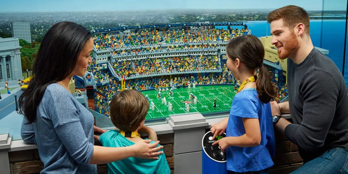 Visitors viewing a football stadium model in MINILAND at LEGOLAND Discovery Center Michigan
